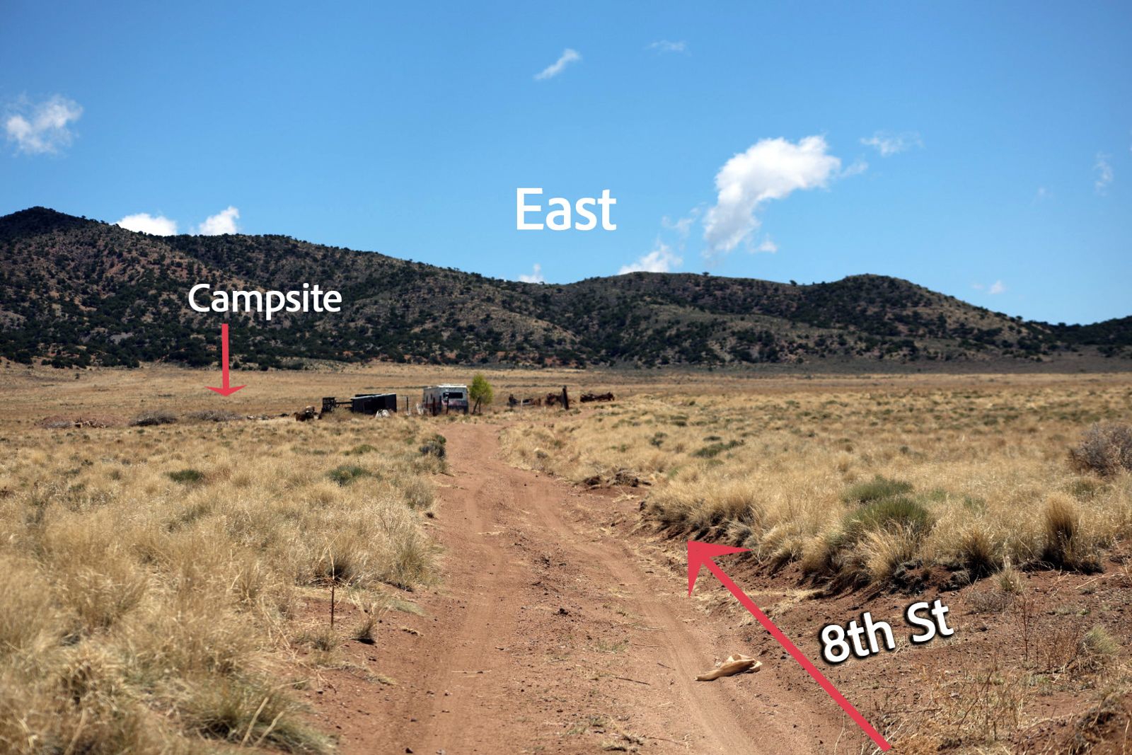 Looking east down 8th Street at an old camper, with the campsite marked beyond it
